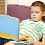 A gyerek a játék laptoppal játszik.